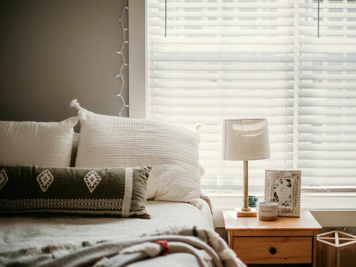 Gemütliches Schlafzimmer mit Fenster und hellen Lamellen